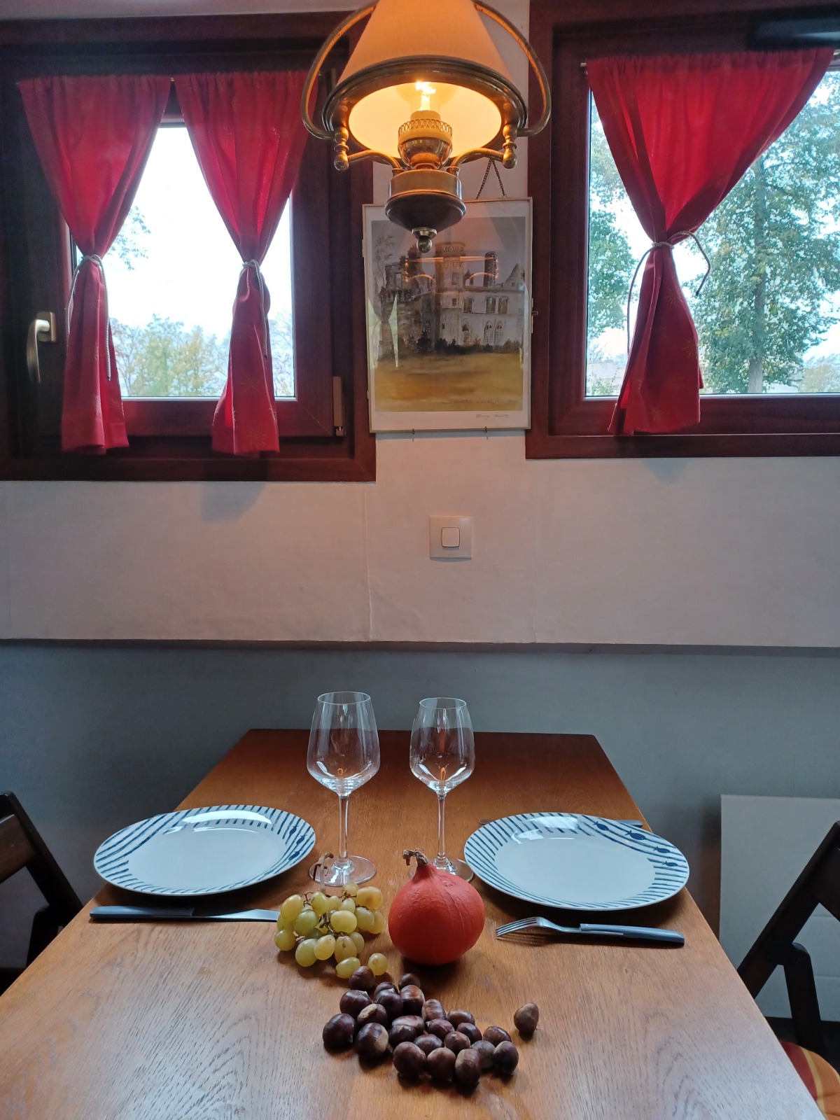 La table dressée près des fenêtres aux rideaux rouges